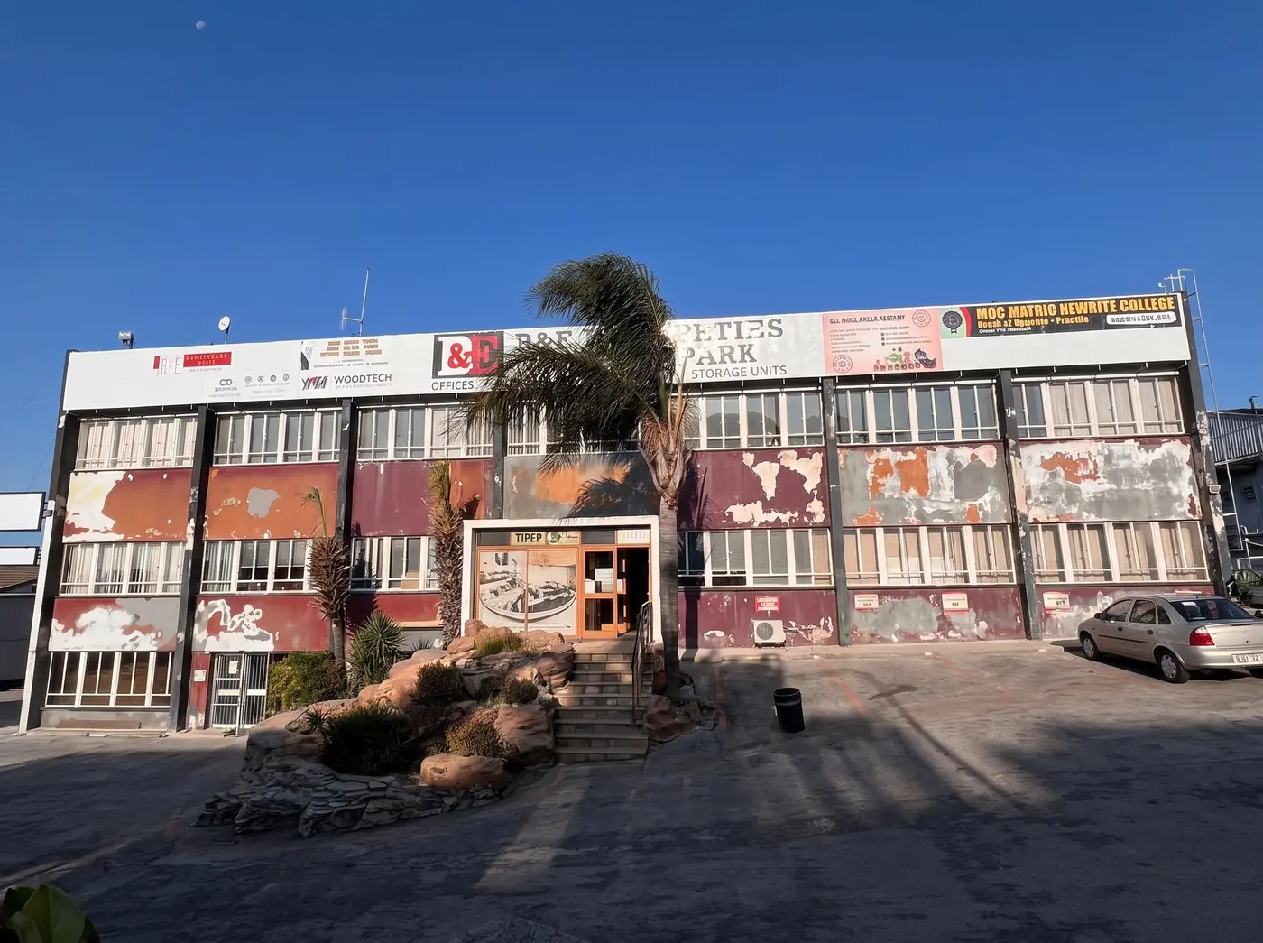 Weathered and patched facade of a commercial office park on Kempston Road, Gqeberha, before repainting by Under Pressure